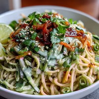 Cold Sesame Noodle Bowl with Cucumber: Refreshing chilled noodles tossed in creamy sesame sauce and topped with crisp cucumber slices and vibrant herbs.
